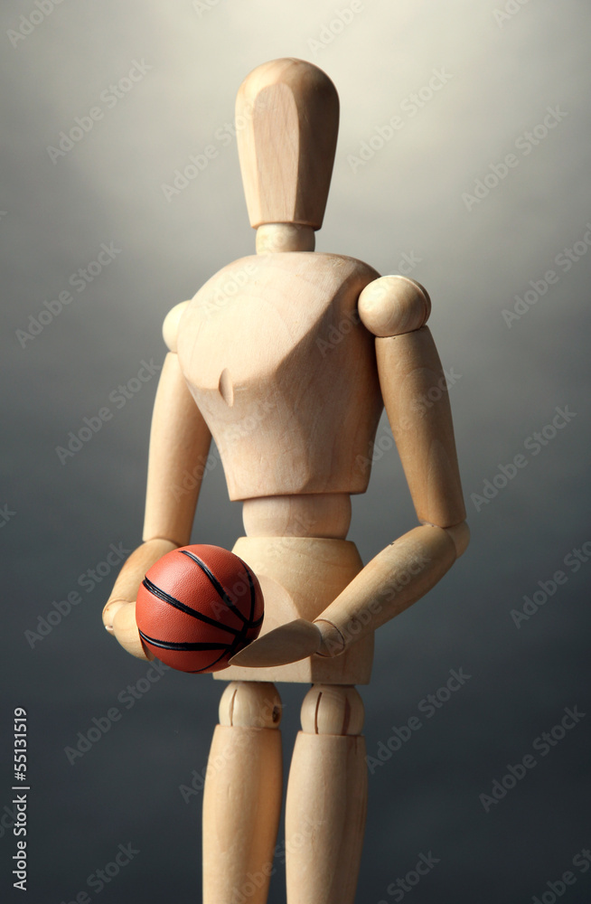 Wooden mannequin with basketball ball on grey background