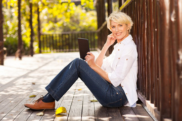 Wall Mural - mid age woman using tablet computer outdoors