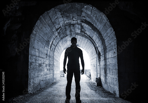 Fotografie, Obraz Man stands in dark tunnel and looks in glowing end