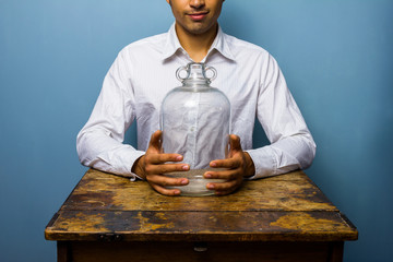 Man holding big empty glass jar