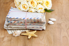 Stack Of Old Letters And Bouquet Of Pastel Yellow Roses On Wood
