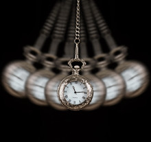 Pocket Watch Swinging On A Chain Black Background