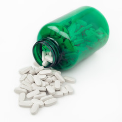 Pills with green medicine bottle on white background