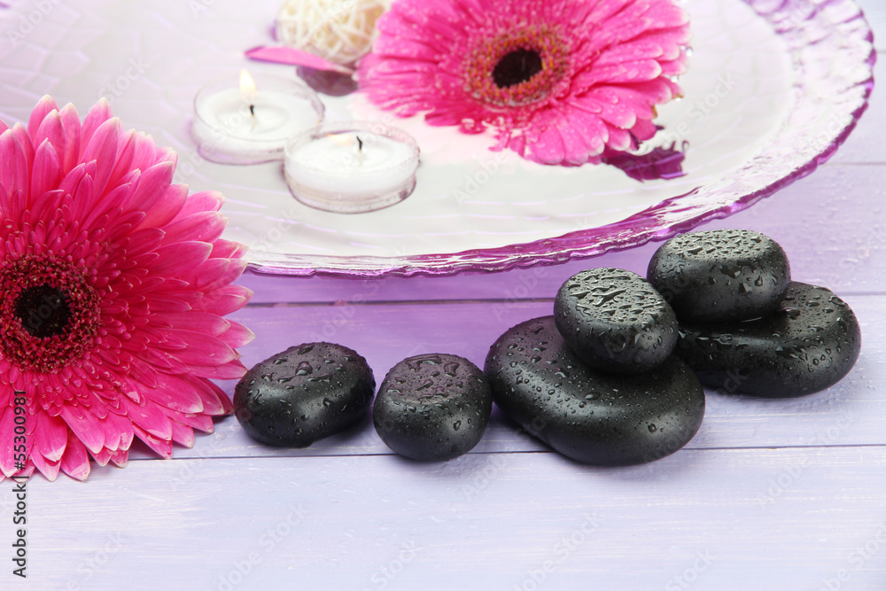 Spa stones, beautiful gerbera flowers and candles on water