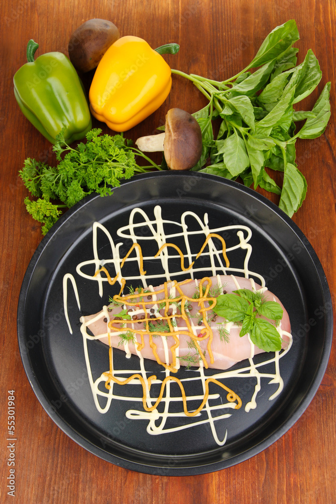 Raw chicken fillets on dripping pan, on wooden background