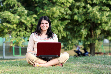 Wall Mural - happy girl with laptop sitting on grass