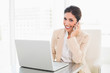 © lightwavemedia - Smiling businesswoman working with a laptop on the phone