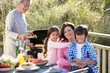 © micromonkey - Grandparents And Grandchildren Having Outdoor Barbeque