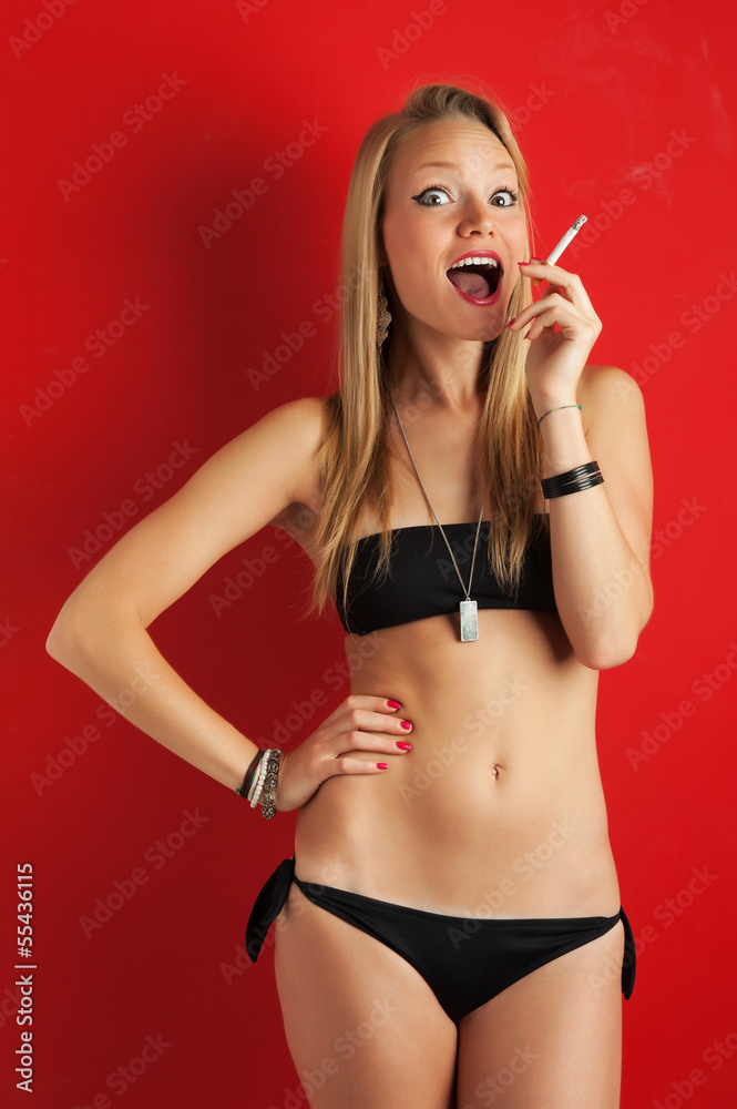 Smoking blonde woman portrait with black bikini on red backgroun Stock  Photo