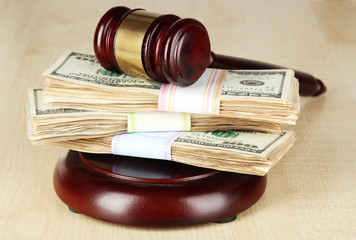 Stacks of money and judges gavel on wooden table