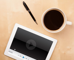 Tablet pc showing media player on screen with a cup of coffee on