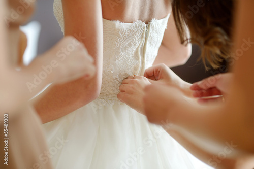 Fotografía Helping the bride to put her wedding dress