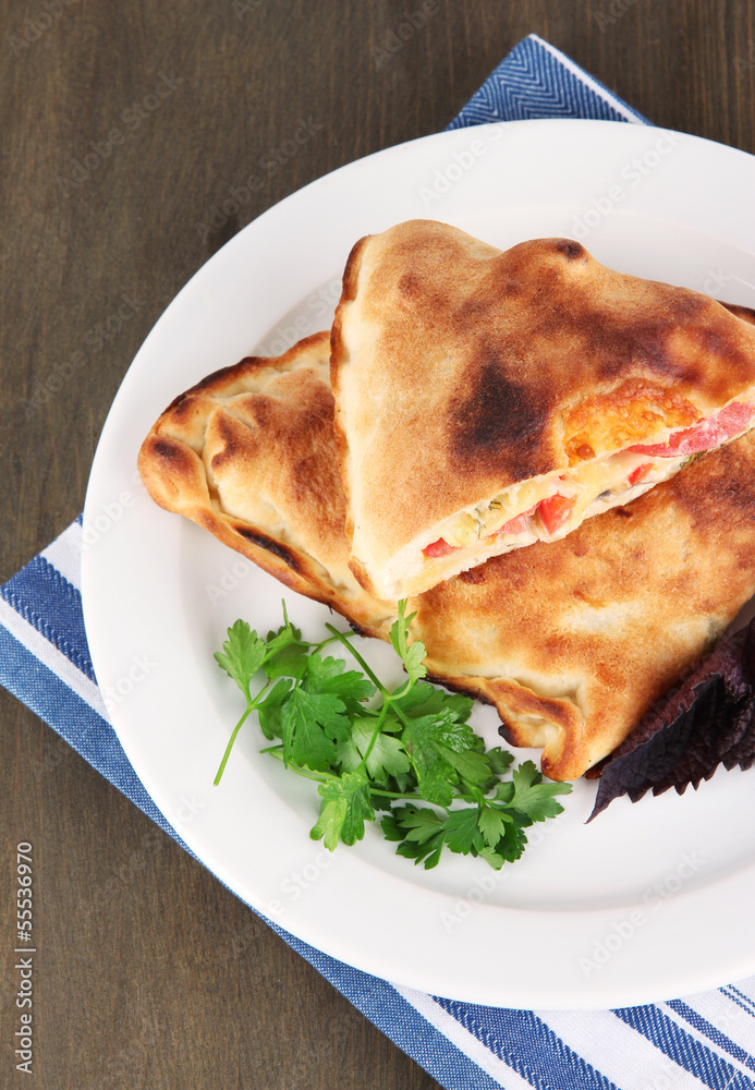Pizza calzone on plate on napkin on wooden table