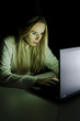 © grufnar - woman working on a computer by night vertical