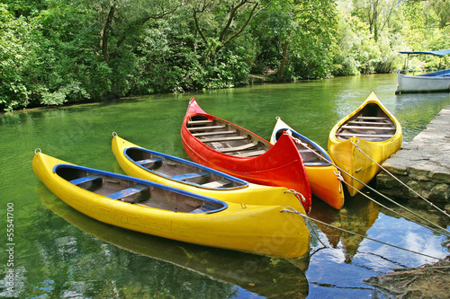 Fotomural Five empty plastic canoes in turquoise green river