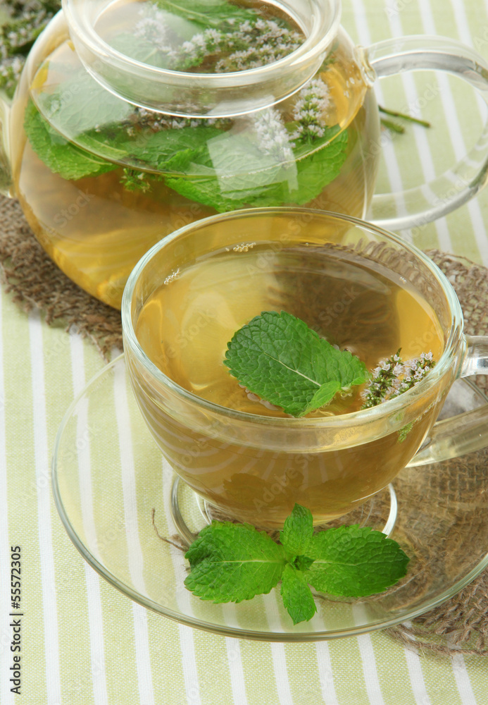 Teapot and cup of herbal tea with fresh mint flowers