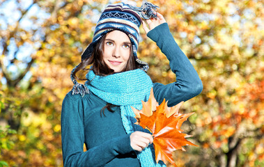 Beautiful girl with leaves on an sunny autumn-day