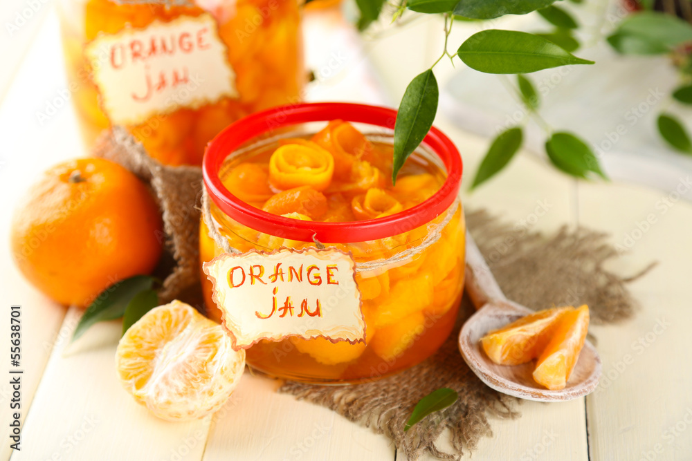 Orange jam with zest and tangerines, on white wooden table