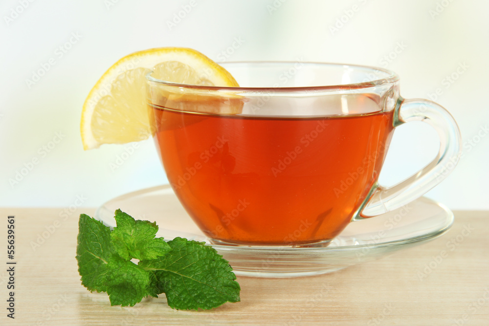 Cup of tea with lemon on table on light background