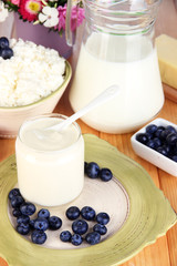 Fresh dairy products with blueberry on wooden table close-up