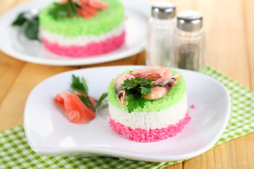 Colored rice on plates on napkin on wooden table