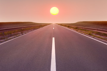 Wall Mural - Driving on empty road towards the setting sun