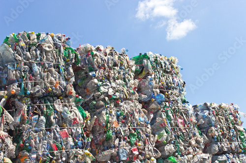 Fotografía Stack of plastic bottles for recycling against blue sky