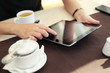 Image of woman hand pointing at tablet touchscreen in cafe