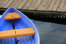 Bright Blue Row Boat Tied To Wood Dock