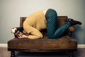 Young man burying his face in old sofa