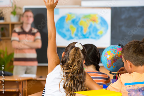 Fotografía Schoolgirl rising her hand at geography lesson