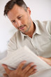 © goodluz - Relaxed handsome man at home reading newspaper