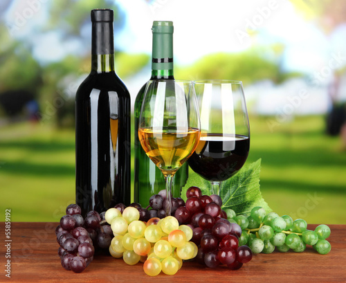 Naklejka na szybę Wine bottles and glasses of wine on bright background