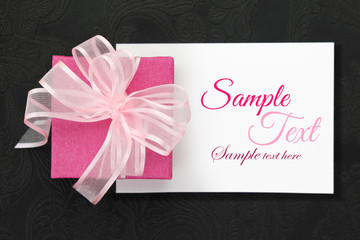 Pink gift box with ribbon on white card