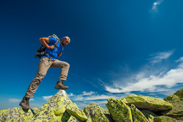 Wall Mural - Hiker jumps over stones in mountains