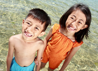 Wall Mural - Close up portrait of happy asian kids in the beach smiling