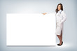© adam121 - young woman doctor standing near a blank banner