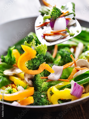 Fotografía spatula stirring vegetables in a stir fry wok.