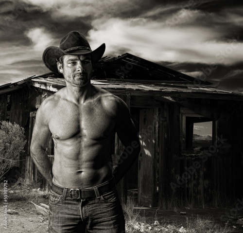 Photo  Cowboy at dusk in front of an old cabin
