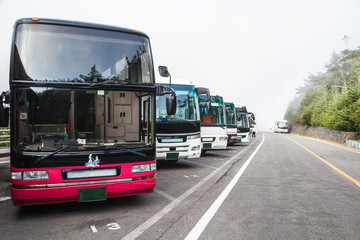 many bus coach are lined up at the parking lot of mount fuji.