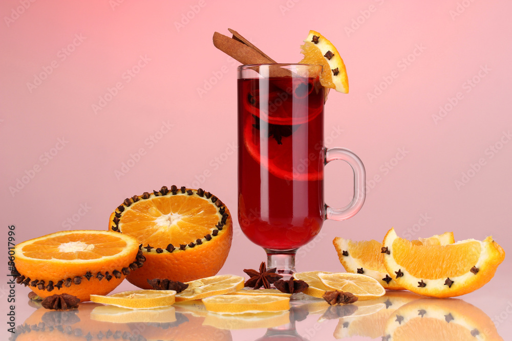 Fragrant mulled wine in glass with spices and oranges around