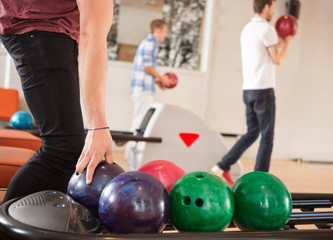  Man Picking Bowling Ball With Friends in Background