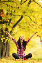 woman drop leaves in autumn park