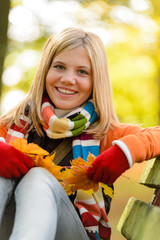 Wall Mural - Autumn cheerful young girl sitting park fall