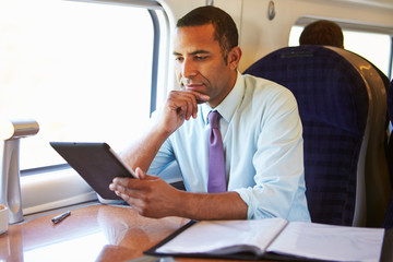 Businessman Commuting On Train Using Digital Tablet