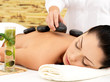 Woman having hot stone massage of back in spa salon