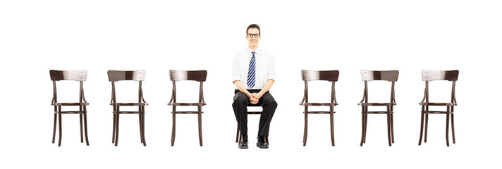 Wall Mural - Young male with tie sitting on a chair waiting for job interview