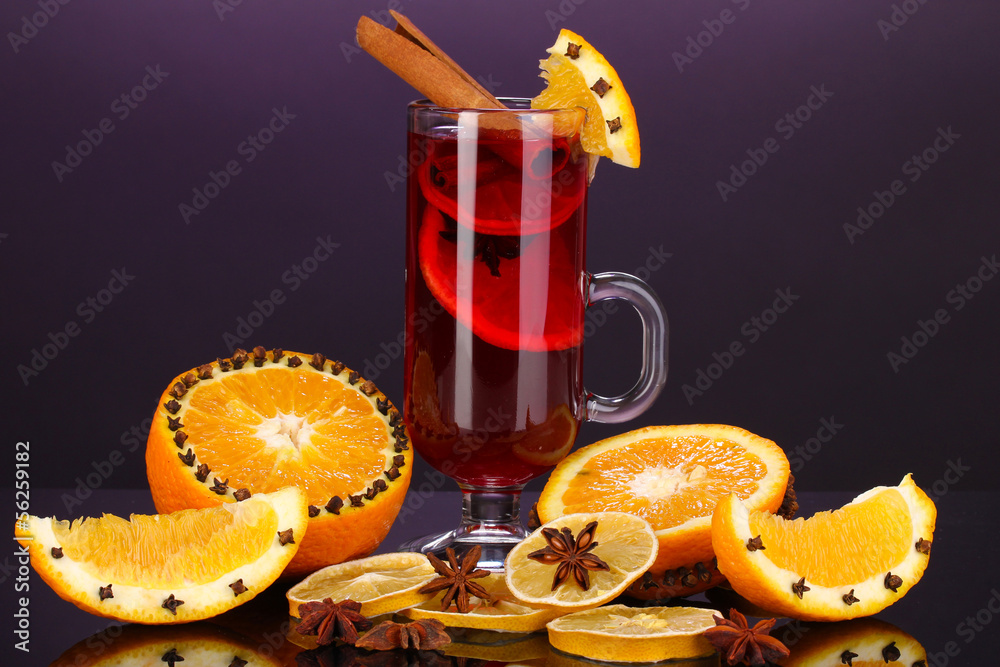 Fragrant mulled wine in glass with spices and oranges around
