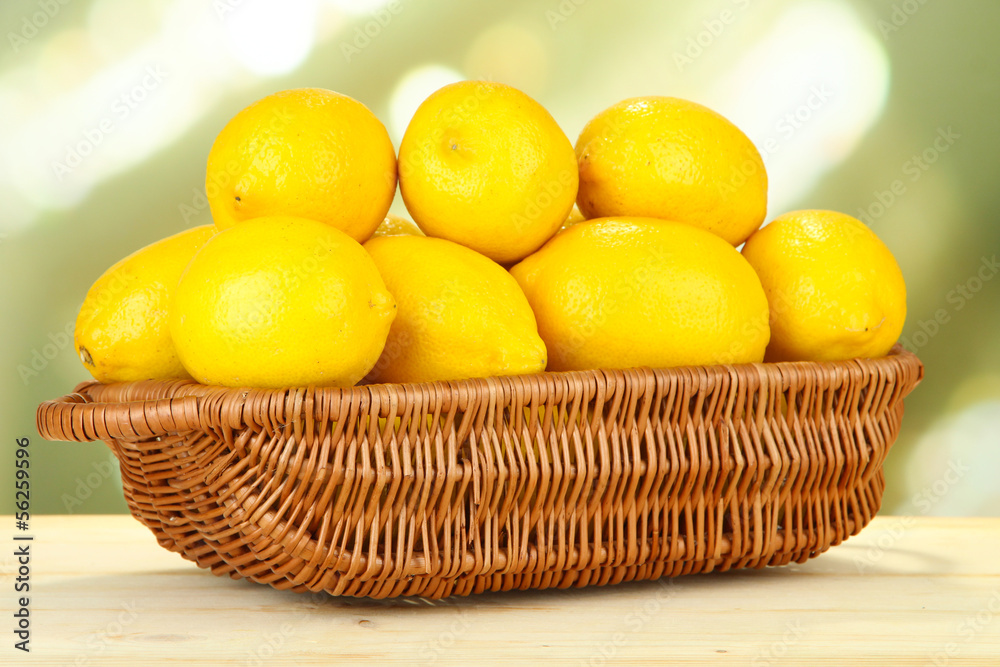 Ripe lemons in wicker basket on table on bright background