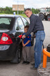 Senior grandfather with young boy refilling car at gas station